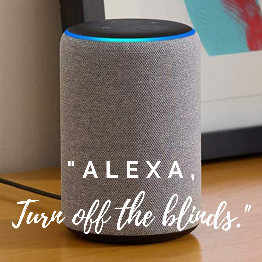 A cylindrical smart speaker with a fabric exterior is positioned on a wooden surface. The speaker has a light ring at the top glowing blue. A framed picture is partially visible in the background. Overlaid text reads, "ALEXA, Turn off the motorized window treatments.