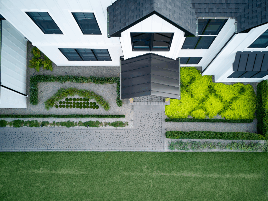 Aerial view of a modern home's entryway with sculptural landscape design by PLANT Design Group, blending architecture with organic form.