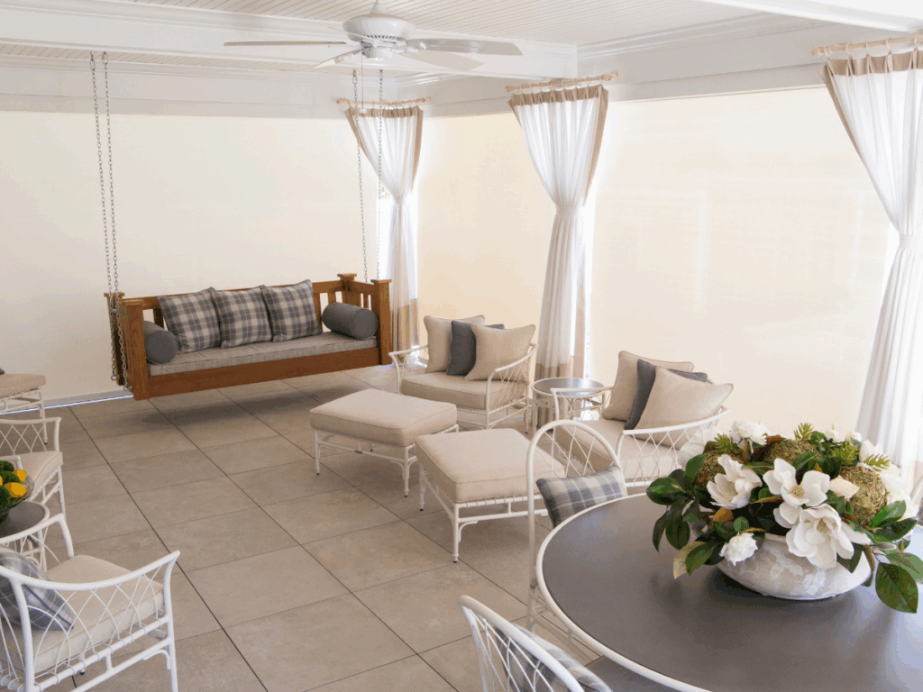 Relaxed seating in a covered patio featuring custom Vitalia Inc motorized outdoor shades for light control and insect protection.